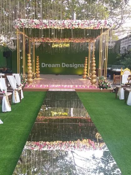 A truly glamorous ceremony setup featuring a floral mandap with a dazzling mirrored aisle. The reflection of the sky and the decor creates a spectacular visual, making the bridal entrance a breathtaking moment.