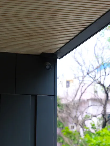 A close-up of a facade corner, showing the junction of MetaWood Flute profiles and MetaCassette Grooved Panels. This detail highlights the rhythmic verticality and structural finesse of the design.