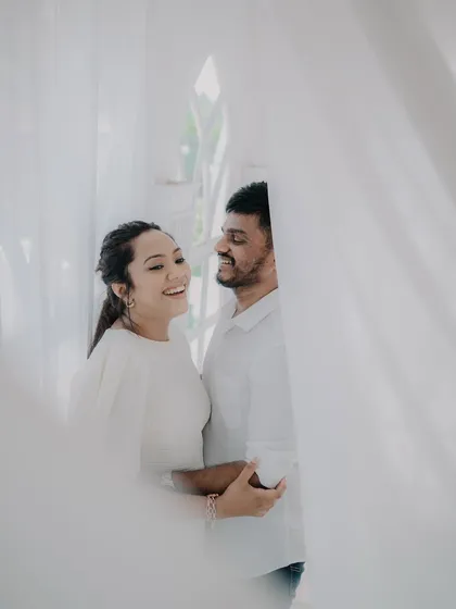 A soft and dreamy shot taken through sheer white curtains. This creative technique adds a layer of intimacy and romance to the couple's portrait.