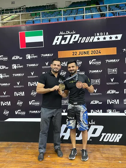 A coach and his fighter celebrating their success at the AJP Tour. This partnership is crucial for success in combat sports.