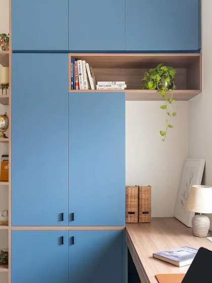 This view highlights the extensive storage in the 'Living Life in Colours' study, with blue floor-to-ceiling cabinets and open wooden niches.