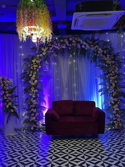 A full view of the Roka stage setup, including the floral arch, side flower stands, and hanging floral chandeliers that match the decor.