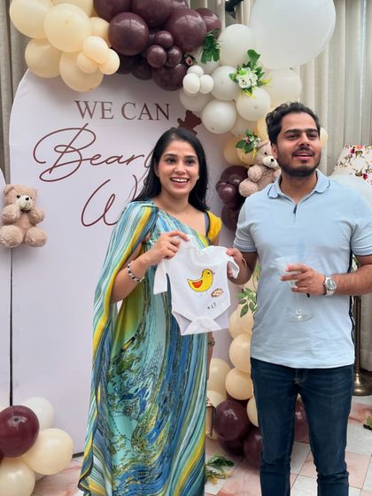 The happy parents-to-be showing off a cute, hand-painted duck onesie made by one of their guests. These creations become cherished keepsakes.