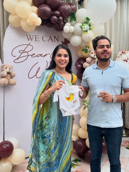 The happy parents-to-be showing off a cute, hand-painted duck onesie made by one of their guests. These creations become cherished keepsakes.