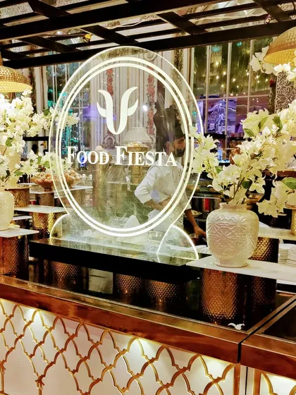 Wedding season is in full bloom, and so is Food Fiesta. An elegant white and gold buffet counter, adorned with white flowers, perfectly complements the luxurious wedding decor.