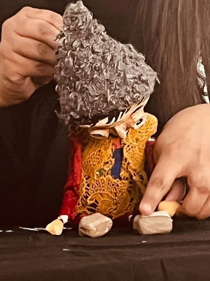 Adjusting the costume of one of our handcrafted puppets. The traditional patterns and textures add so much character.
