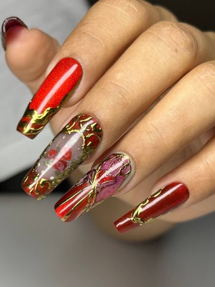 A dramatic and luxurious nail art set on extra-long square extensions. The design features a deep red base with intricate gold details and a transparent accent nail with a rose inside.