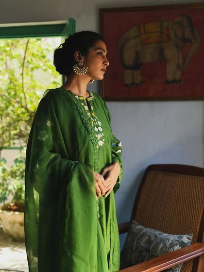 A serene portrait for the clothing brand Baavli. The model, dressed in a beautiful green embroidered suit, looks out a window, creating a painterly image that feels both timeless and deeply personal.