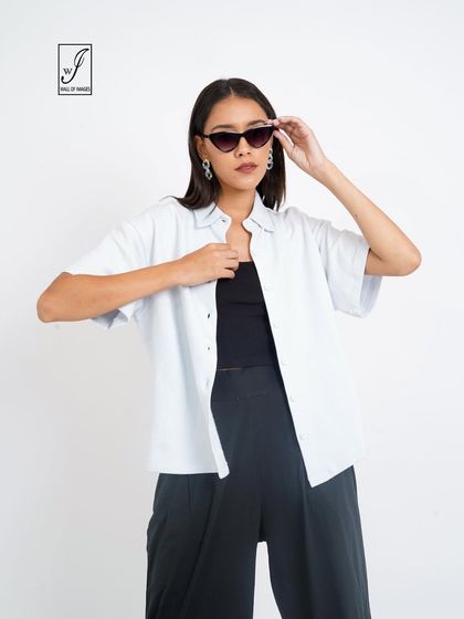 A simple and stylish look with a white shirt over a black top and trousers, perfect for a minimalist brand.