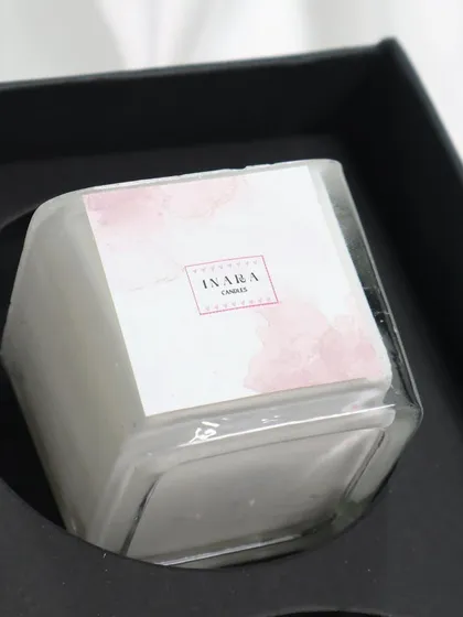This white candle, part of a curated gift set, offers a clean and classic look. The minimalist label and clear glass jar make it a versatile choice for any decor.