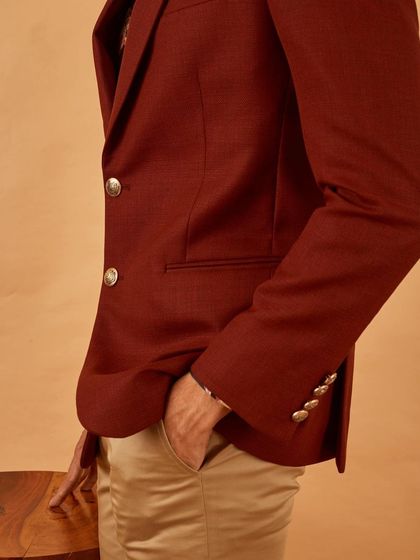 A side profile of our maroon blazer, showing the custom gold buttons and the perfect fit around the shoulders.