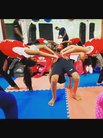 Teamwork makes the dream work. Here, students help each other practice their bridge poses, creating a supportive and collaborative training atmosphere.