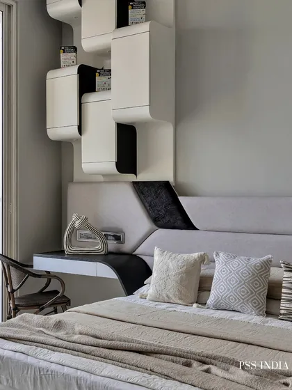 This bedroom showcases bold, modern design with its striking black and white theme. The custom-designed headboard and integrated shelving create a unique, sculptural feature that is both artistic and functional.