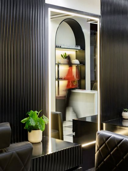 The view from the client's perspective is paramount. The large, illuminated mirror at each cutting station not only provides excellent light but also reflects the salon's elegant design, including the arched entrance to the manicure area.