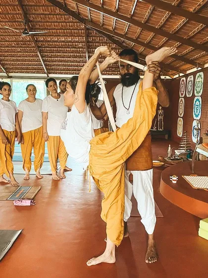 This is another view of me assisting a student in a standing split, using a strap for support. We teach multiple ways to approach and assist in advanced postures.