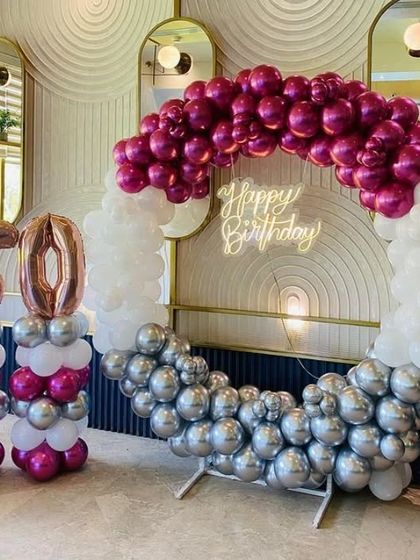 A glamorous 60th birthday party with a balloon ring in magenta, white, and silver, and large foil numbers.