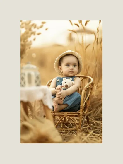 A closer portrait of the child in the wheat field, holding a small teddy bear. His curious and innocent gaze is the focus here, with the soft, golden light beautifully illuminating his features.