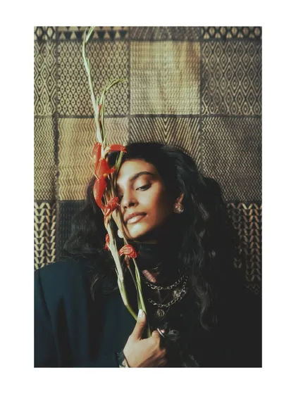 A tender moment from 'Roots', where the model holds a flower to her face. This image introduces a natural, organic element, connecting personal growth to the resilience of nature.