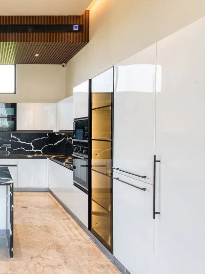 This view highlights the full-height, integrated appliances and the smoked glass pantry, which is internally lit to showcase its contents.