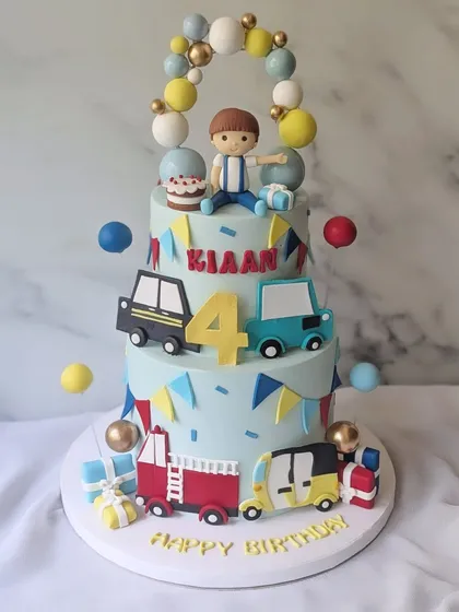 A fun vehicle-themed cake for a little boy who loves all things that go, especially his favorite auto-rickshaw. This three-tier cake is decorated with cars, a fire truck, and a balloon arch.
