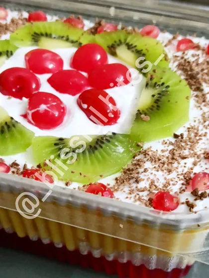 My colorful and festive Mixed Fruit Trifle, perfect for any celebration. This party-sized dessert features layers of jelly, custard, cake, and fresh cream, beautifully decorated with kiwi, cherries, pomegranate seeds, and a sprinkle of chocolate.