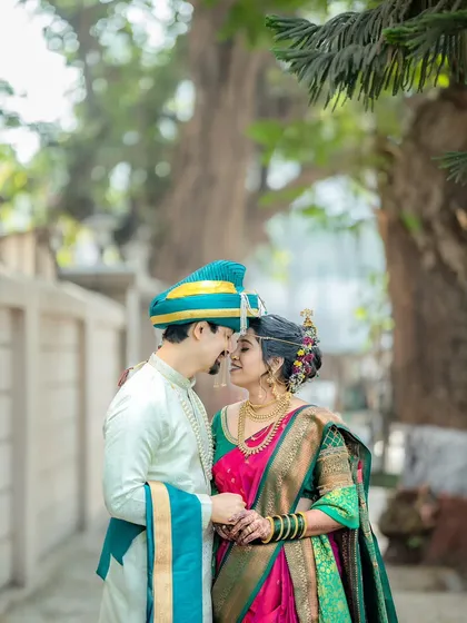 A romantic portrait of a traditionally dressed Maharashtrian couple, framed by lush greenery that adds a natural softness to the image.