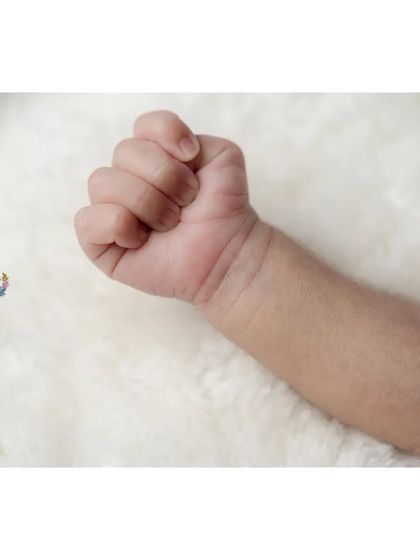 A tiny, perfect fist against a soft white blanket. It's a simple, powerful image that captures the strength and delicacy of a newborn.