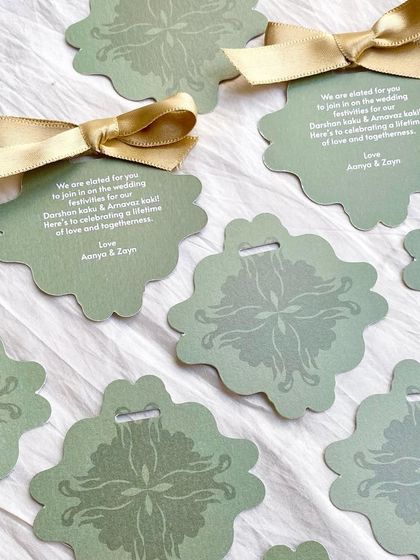 Pretty, custom-shaped gift tags for Mehendi favors. The sage green color and subtle pattern, finished with a gold ribbon, are an elegant way to thank guests.