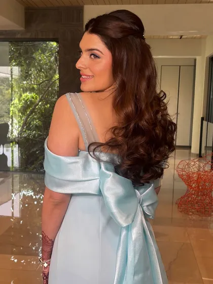 A beautiful engagement look with a half-up style and voluminous curls. The big bow on the back of her dress adds a touch of drama.