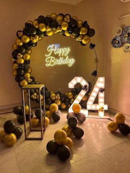 A stylish black and gold theme for a 24th birthday. The circular balloon arch and light-up numbers create a sophisticated photo corner.
