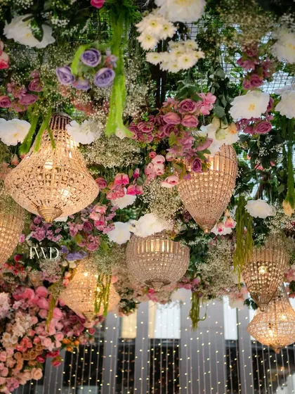 The interplay of light and flowers in our upside down garden. The warm glow from the chandeliers illuminates the delicate petals, creating a romantic and magical ambiance for an evening ceremony.