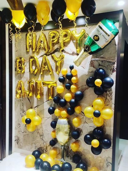 A fun birthday setup for an adult with a champagne bottle foil balloon and a black and yellow theme.