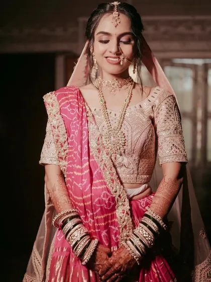 The bride's serene expression captured perfectly. The soft pink makeup complements her Bandhani dupatta and pastel lehenga.