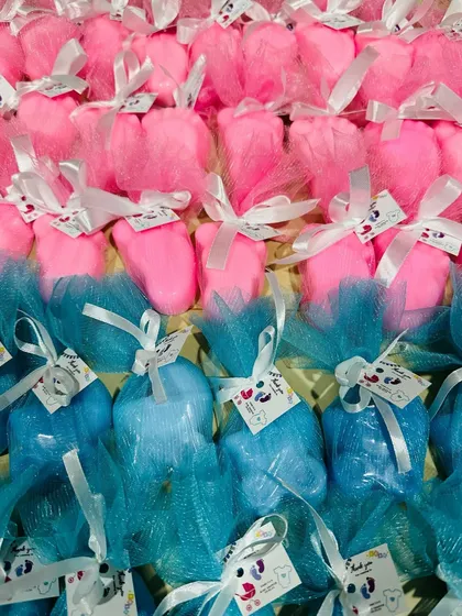 Adorable baby shower return gifts. These are handmade goat milk and almond oil soaps in baby feet and pram shapes, beautifully packaged in pink and blue net pouches.