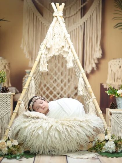 A peaceful moment in our boho paradise. The baby is swaddled in white, contrasting beautifully with the natural tones of the surrounding decor.