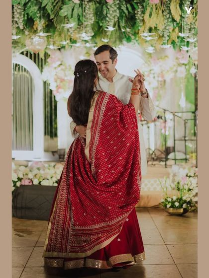 A beautiful moment of the couple dancing together, the bride's red bandhani dupatta flowing around them. It’s a snapshot of joy and celebration.