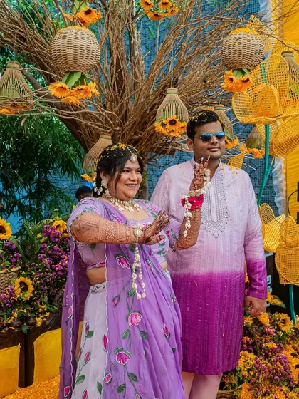 The couple dancing together at their Haldi, framed by the unique backdrop of sunflowers and woven basket lanterns.