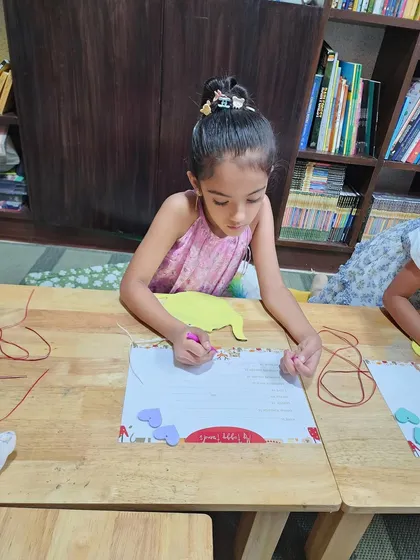 A young girl carefully works on her craft project at the wooden table. These creative moments allow children to express themselves and create something they can be proud of.