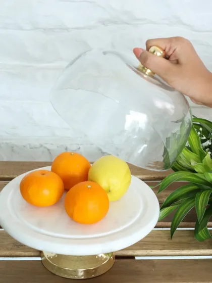 Lifting the glass cloche to reveal fresh citrus on our white marble and gold cake stand. This piece is as functional as it is beautiful, perfect for any modern kitchen.