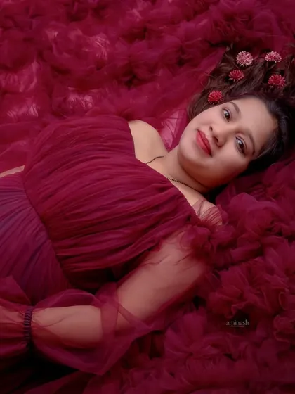 Another creative use of fabric, this overhead shot envelops the mother-to-be in a sea of rich, maroon ruffles. The flowers in her hair add a delicate, personal touch.