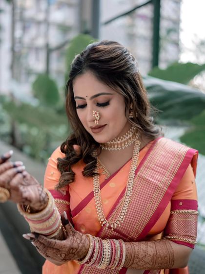 The bride is adjusting her bangles, giving a great view of her soft makeup and beautiful hairstyle.
