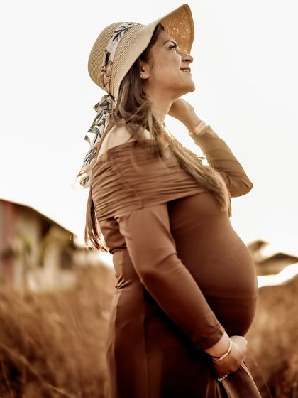 A hopeful portrait of the mom-to-be looking up towards the sun, her face lit by the warm golden light.
