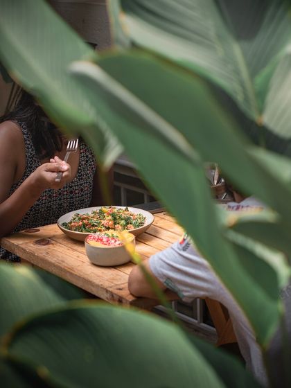 A peek through the leaves at a quiet lunch moment. Our garden provides a lush, private-feeling space to enjoy your meal.