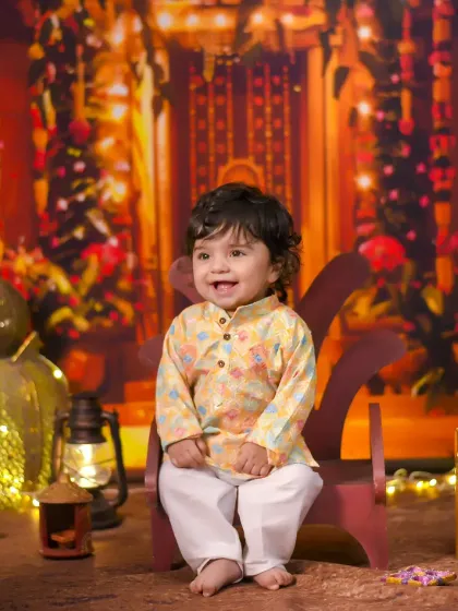 Celebrating baby's first Diwali in a traditional kurta. The warm, glowing backdrop creates a beautiful and authentic festive atmosphere.