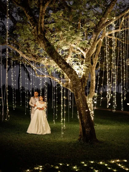 A magical night shot of the couple under a tree adorned with cascading fairy lights.