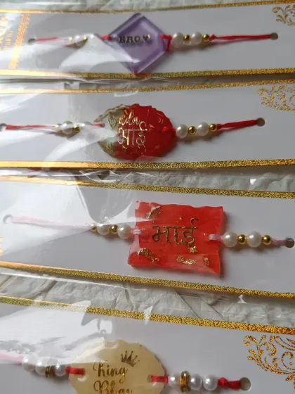 Here is a selection of my handmade resin rakhis. You can see different shapes and colors, with messages like 'Bhai' and 'King Bhai' to celebrate your brother.