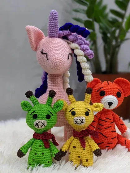 A set of handmade crochet animals, including a unicorn, tiger, and two giraffes.