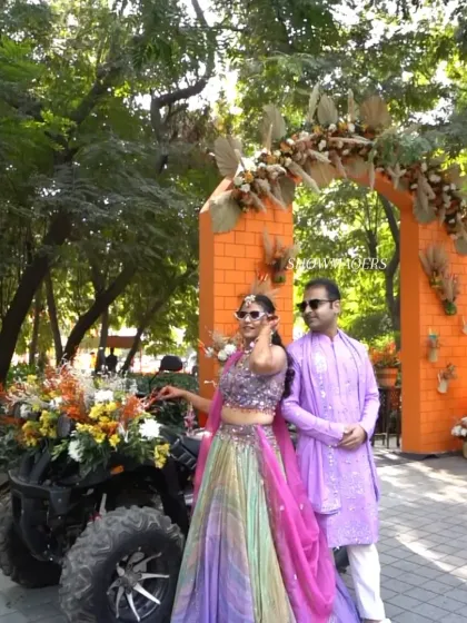 The happy couple posing for a photo by the decorated ATV and floral arch.
