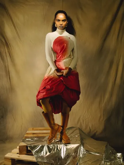 A powerful stance from the 'ANAINA' series, with the model wearing a custom-draped garment. The lighting and pose create a look that is both regal and contemporary.