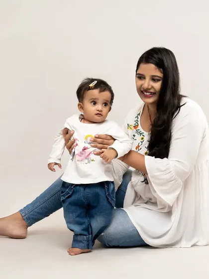 Guiding her first steps. This tender moment between mother and daughter captures a huge milestone with simplicity and love against a clean, timeless backdrop.